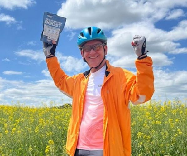 Cyclist holding up a pouch of BOLD Health Protein Boost